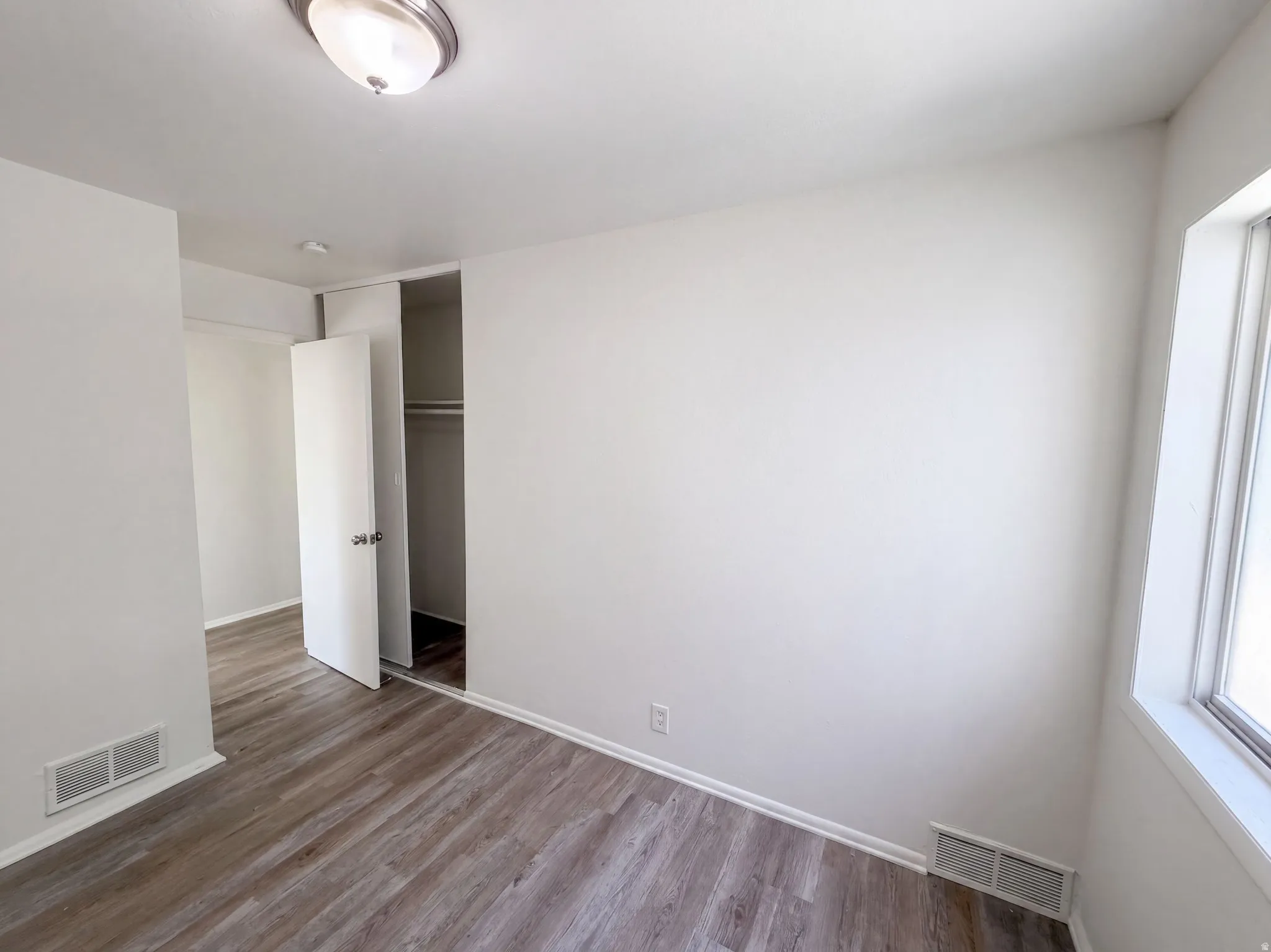 Wood-finish flooring, white painted walls, and a semi-flush mount ceiling light