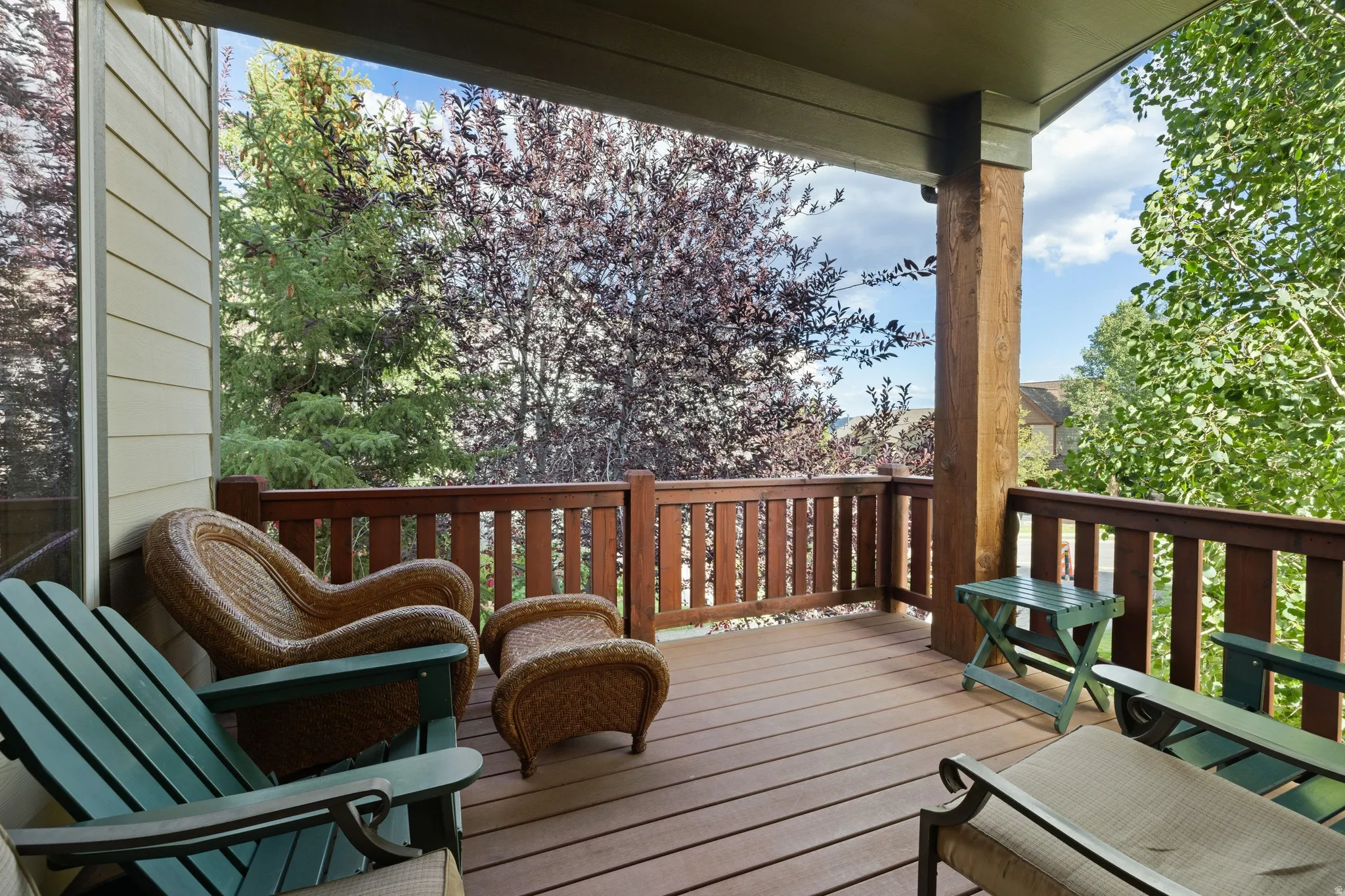 Covered deck with composite wood-finish flooring, wooden railings, and integrated support columns