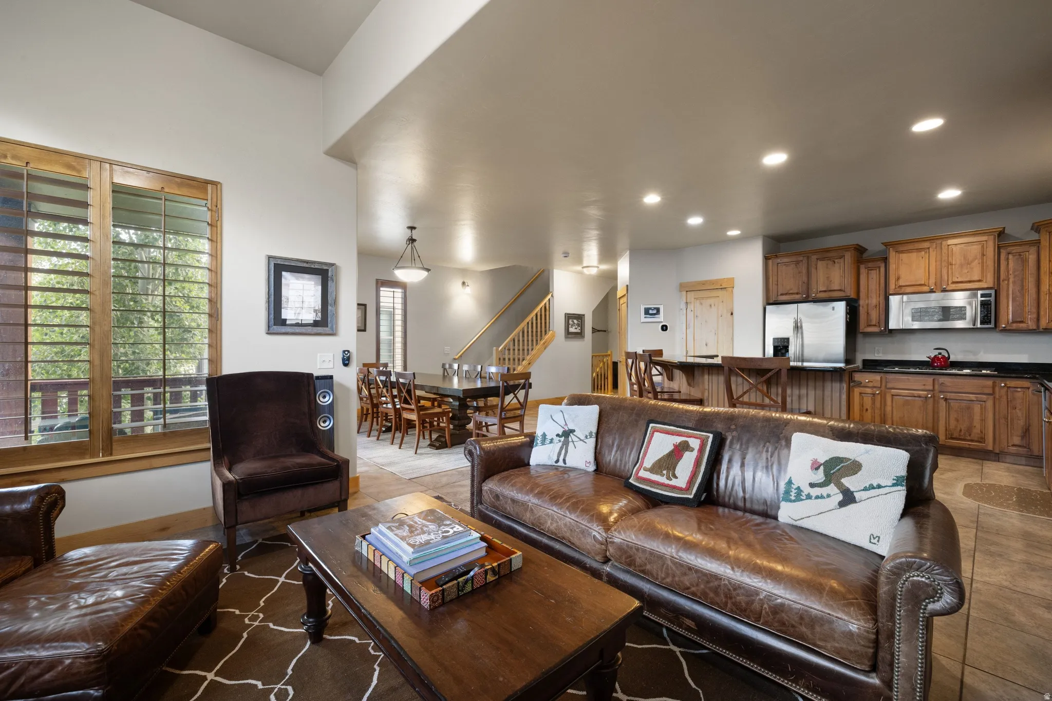 Open-concept living area with recessed lighting, wood-finish cabinetry, stainless steel appliances, and a built-in kitchen island