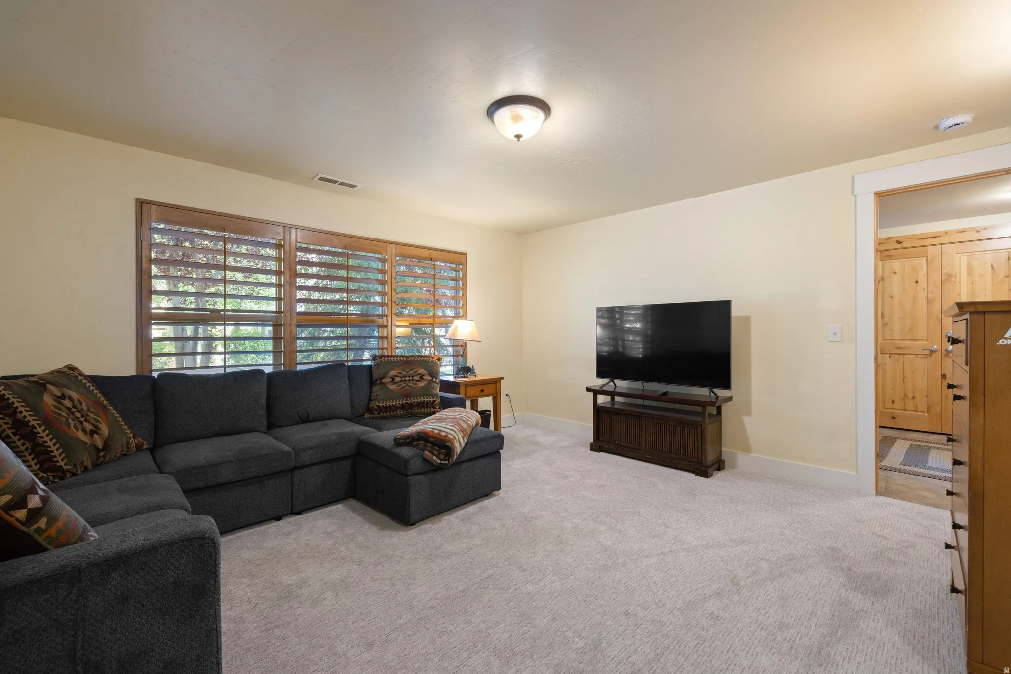 Spacious recreation room featuring a sectional-ready layout, neutral carpeting, and ample natural light from large sliding glass doors with integrated shelving