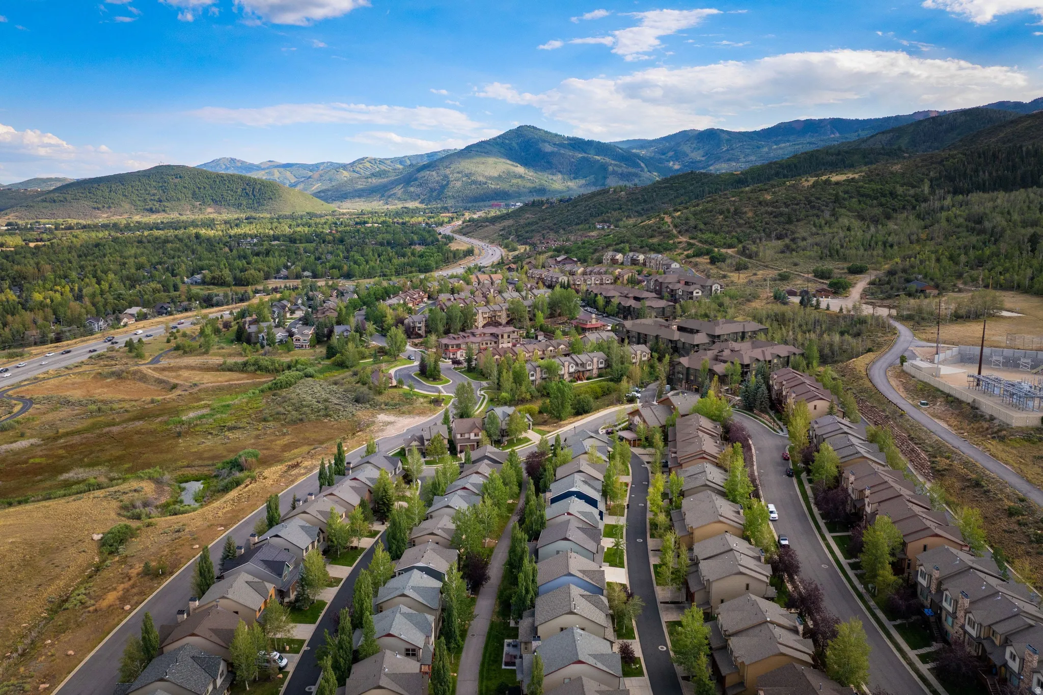 Residential neighborhood with multiple properties, winding roads, and surrounding natural landscape