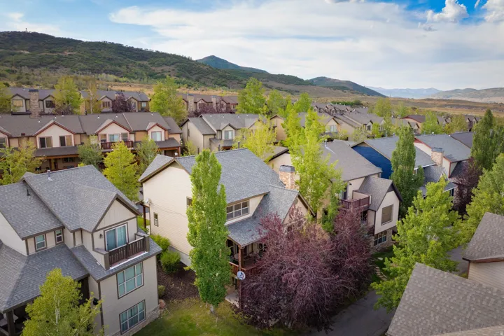 Established residential community nestled against mountain backdrop, featuring multiple two-story homes with varying architectural styles, composite or asphalt shingle roofing, and mixed exterior finishes in neutral tones