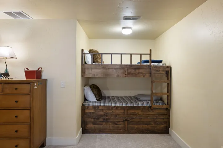 Bedroom featuring built-in bunk beds with wood-finish frames and storage drawers, complemented by wood-finish dresser with multiple drawers