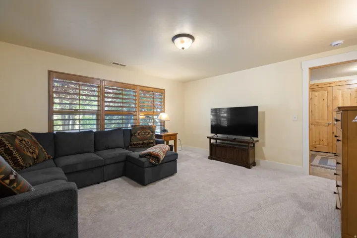 Spacious recreation room featuring a sectional-ready layout, neutral carpeting, and ample natural light from large sliding glass doors with integrated shelving
