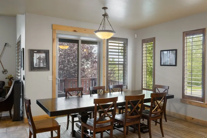 Dining room featuring a wood-finish table with seating for six, hardwood flooring, and abundant natural light from multi-panel glass doors and transom windows
