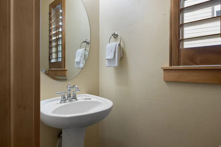 Powder room featuring a classic pedestal sink with chrome faucet, oval mirror, and soft neutral wall finish