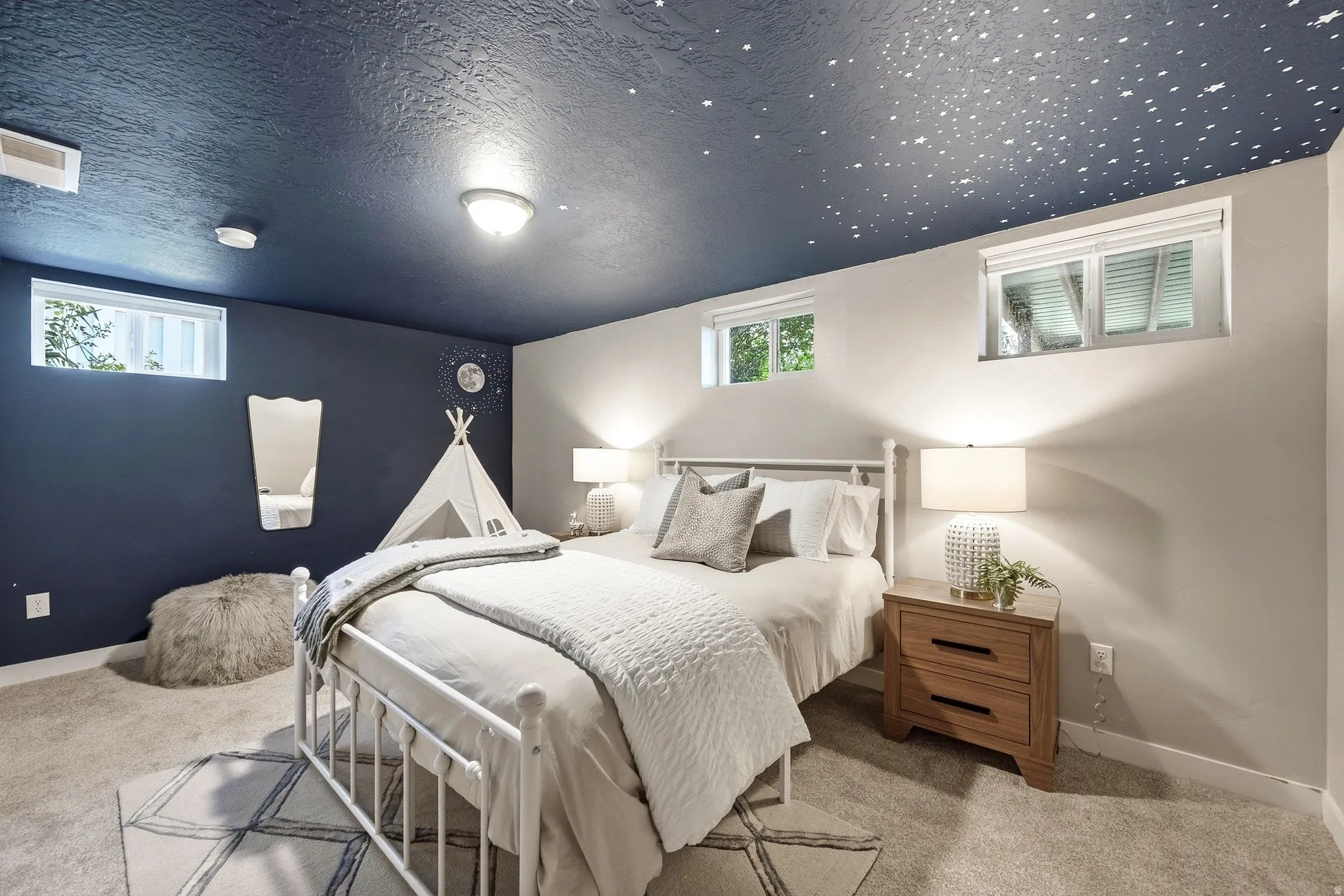 Luxurious bedroom retreat featuring a metal frame bed, soft neutral bedding, wood-finish nightstands with integrated lighting, and plush area rug