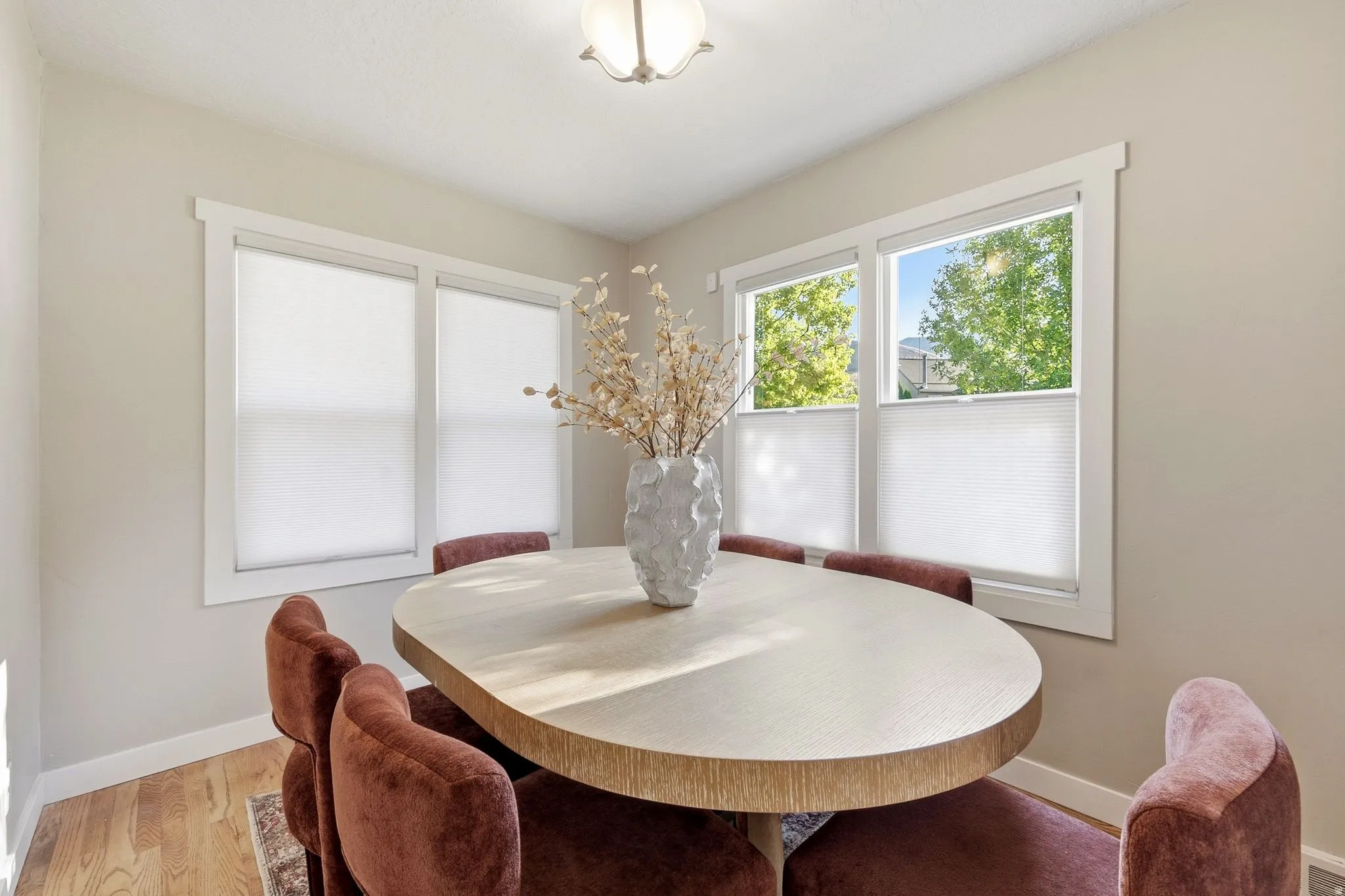 Recessed ceiling light fixture, two large windows, wood-finish flooring, and light wall paint