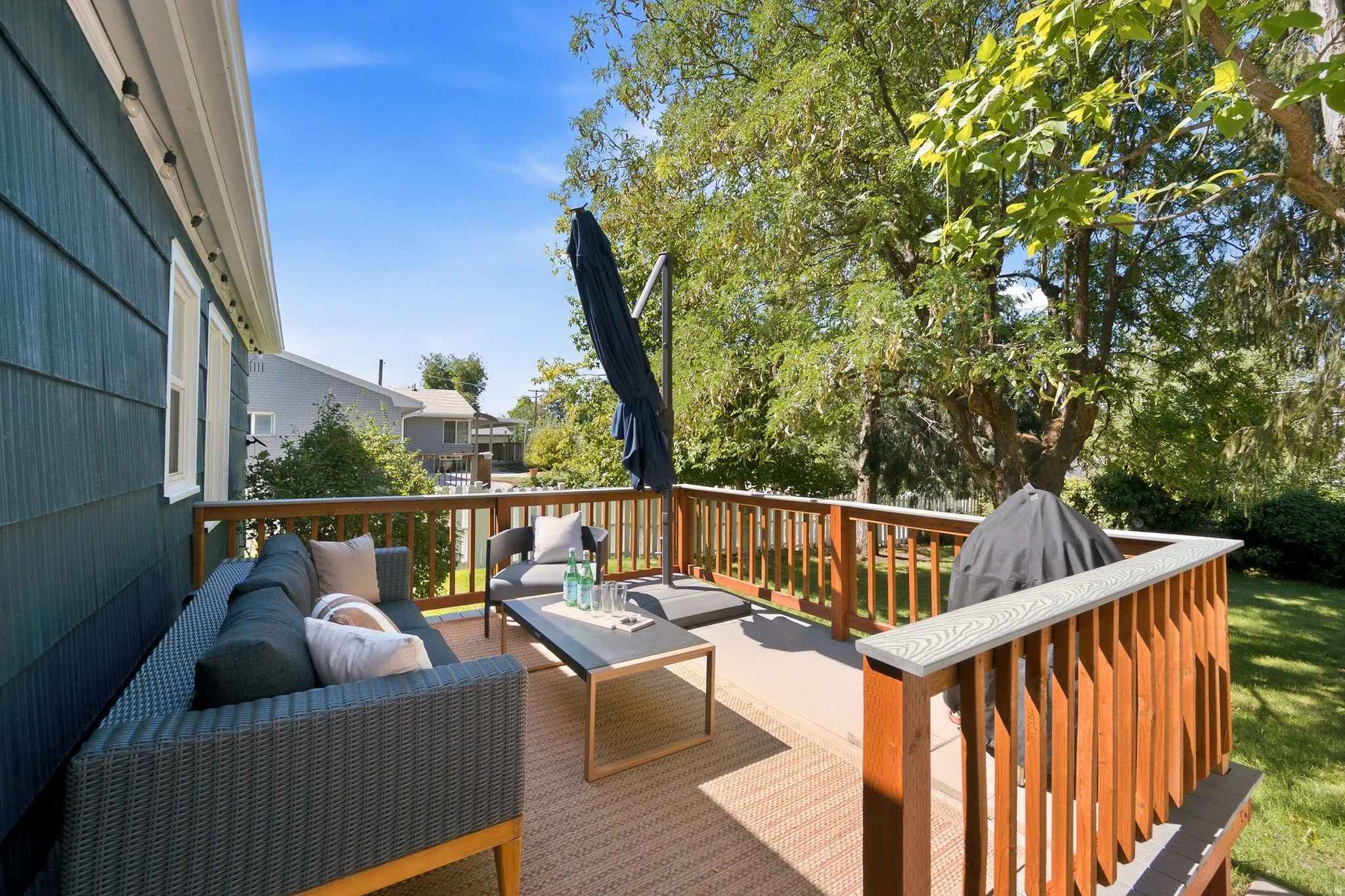 Expansive composite deck featuring wood-finish railings and multiple seating zones, overlooking mature landscaping and tree-lined grounds