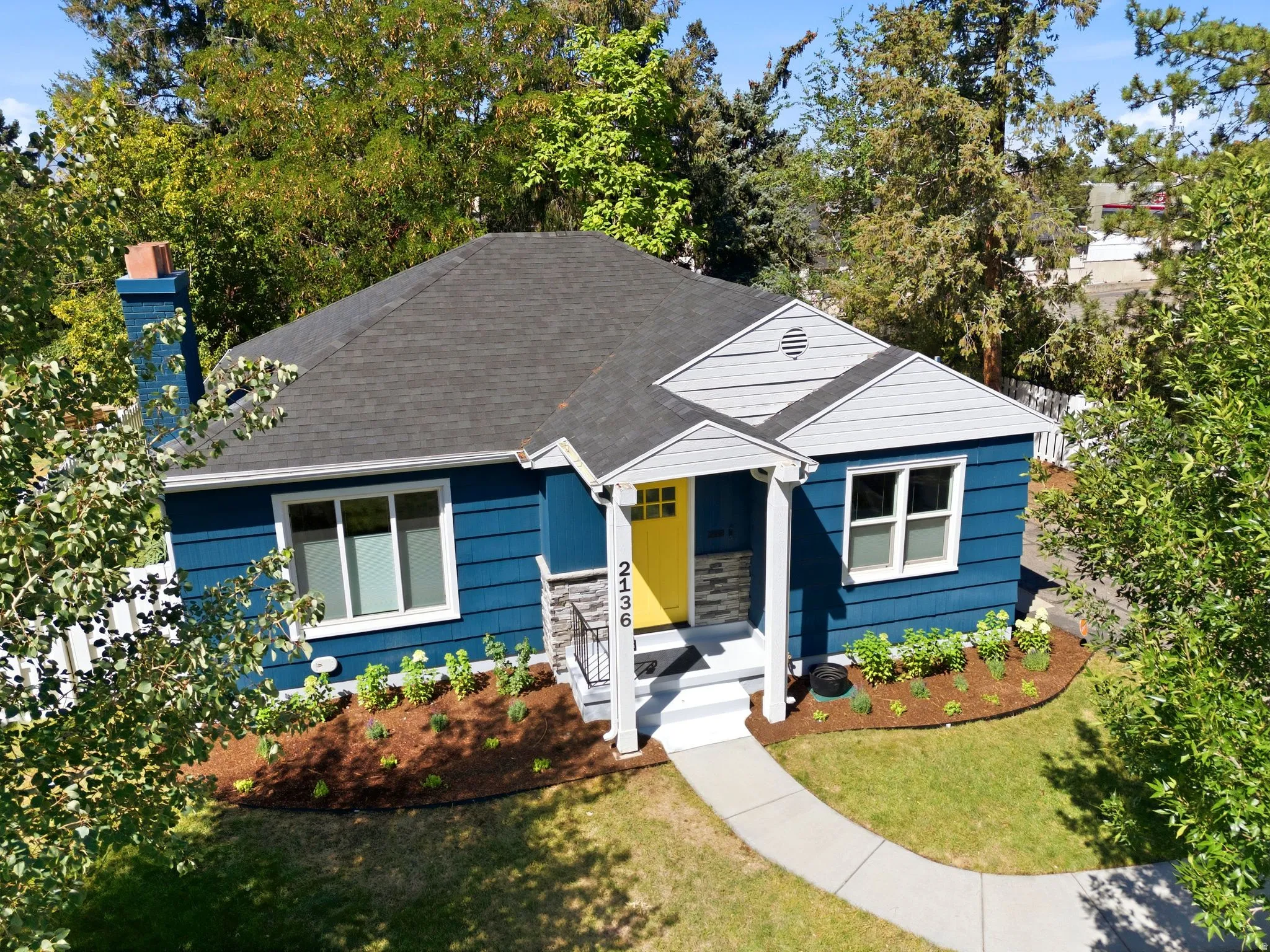 Blue siding exterior with contrasting white trim, dark shingle roof, and a vibrant yellow front door