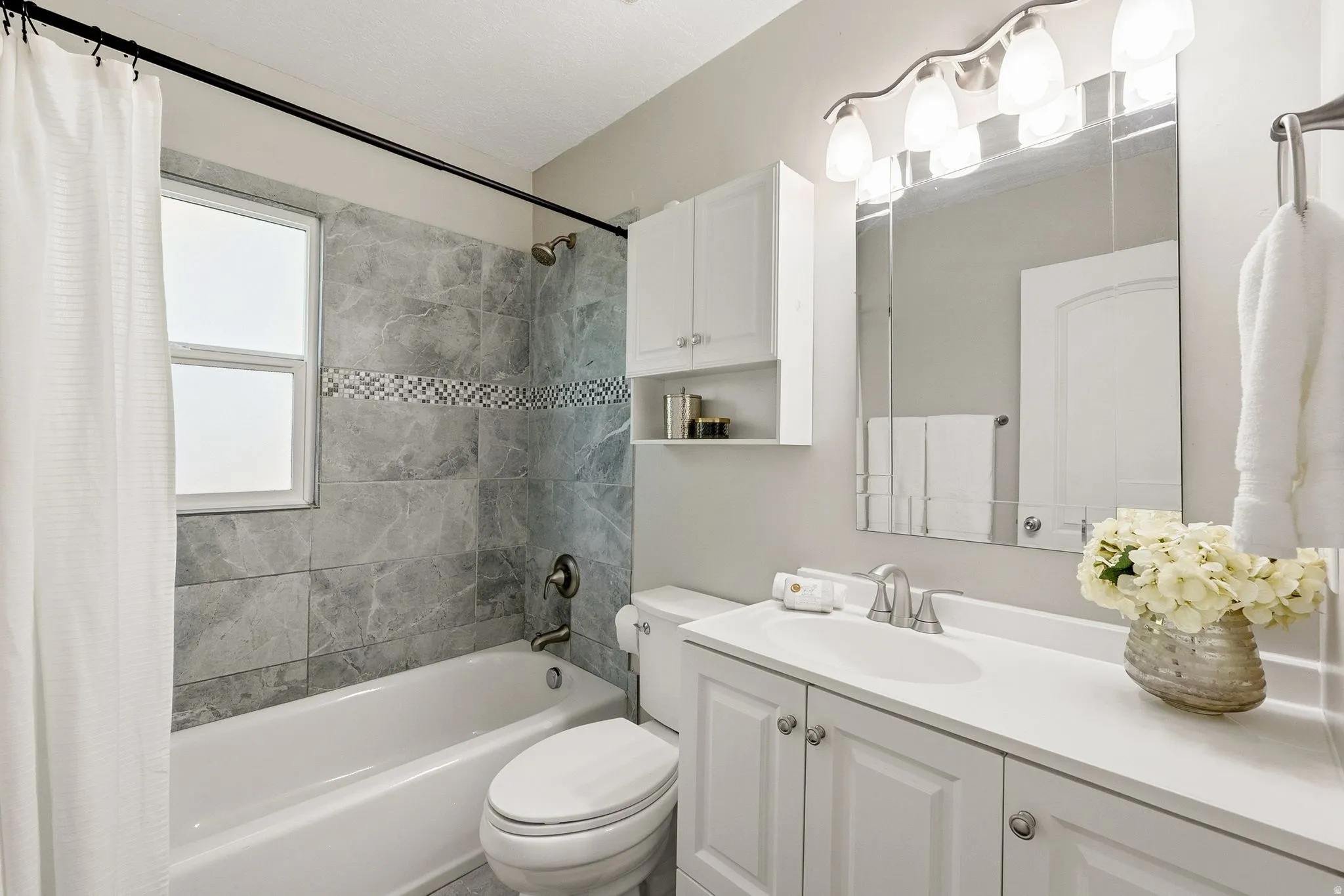 Spa-inspired bathroom featuring a white vanity with dual sinks, polished chrome fixtures, and ample countertop space