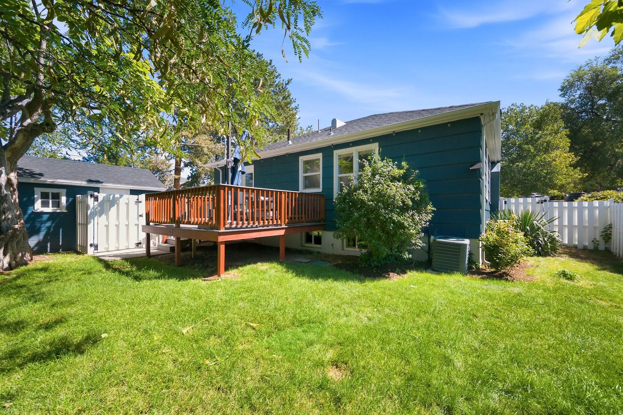 Spacious backyard with mature landscaping and established trees providing natural shade