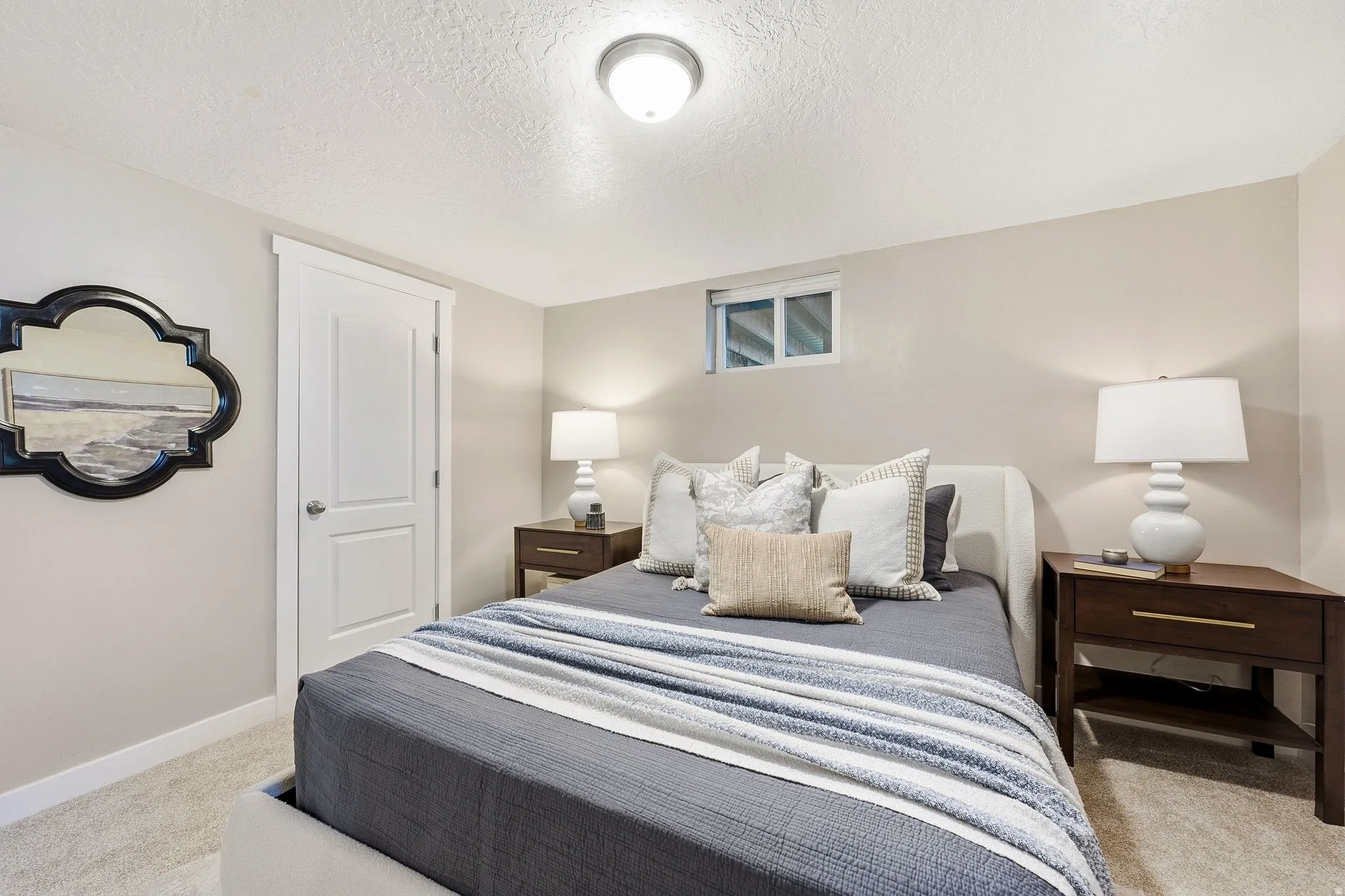 Bright secondary bedroom with neutral wall finishes, recessed ceiling lighting, and wood-finish nightstands flanking the bed