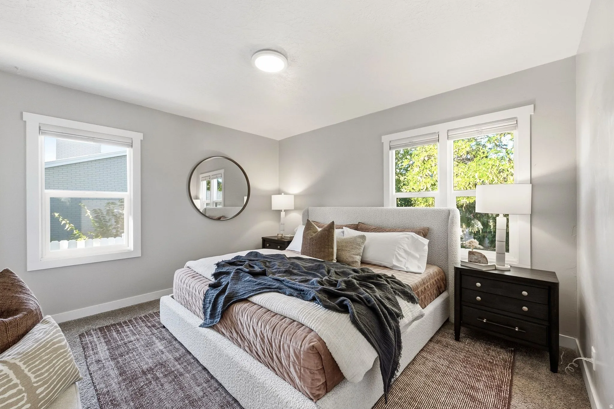 Bright secondary bedroom showcasing neutral gray walls, recessed ceiling lighting, and abundant natural light from dual windows