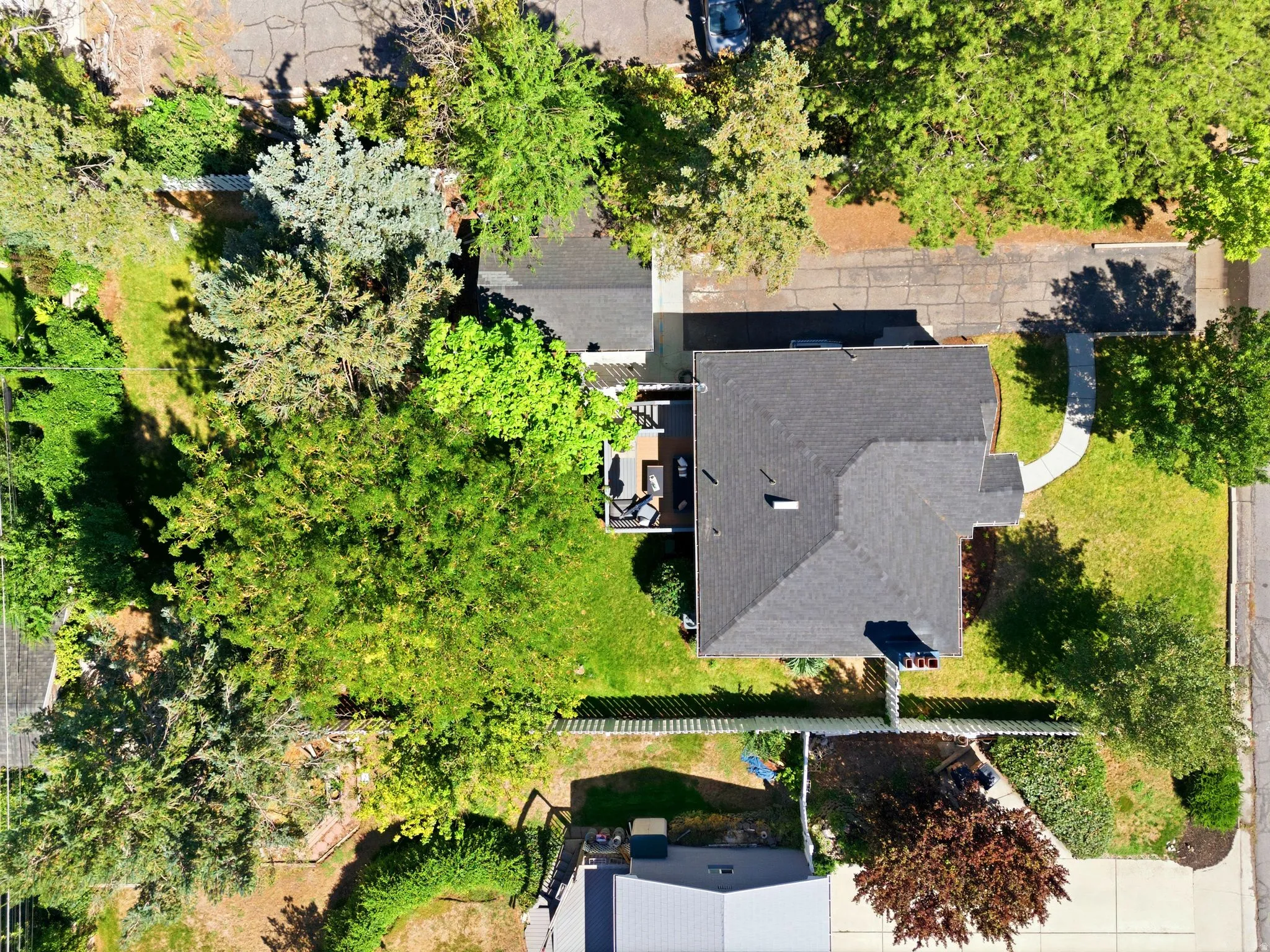.23 Acre lot, detached garage, home with deck, charcoal-gray asphalt shingle roof, surrounded by mature landscaping and established trees