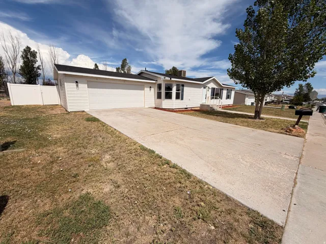White siding exterior with a dark shingle roof, attached garage, concrete driveway, and front entryway with steps and railing