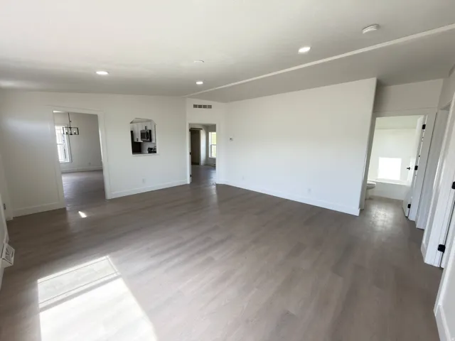 Recessed lighting, light wood-finish flooring, white walls, arched wall opening, and interior doors with black hardware