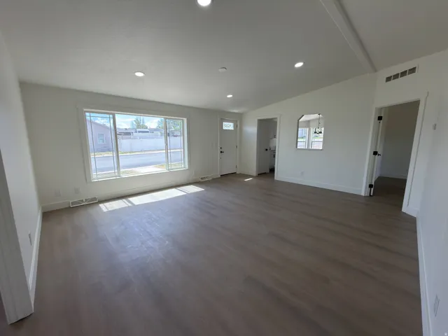 Spacious living area featuring wood-finish flooring, recessed lighting, and a large multi-pane window