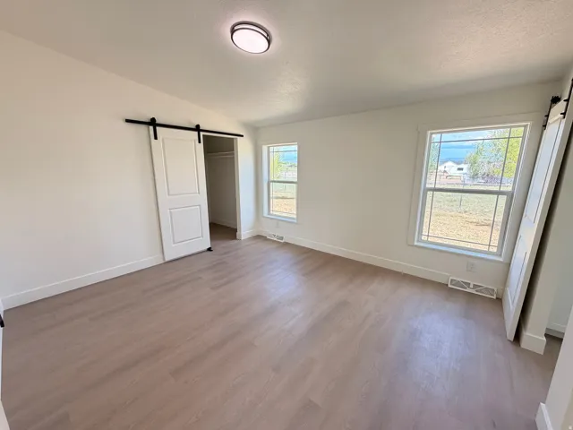 Wood-finish flooring throughout, bright white walls, and two windows with white trim
