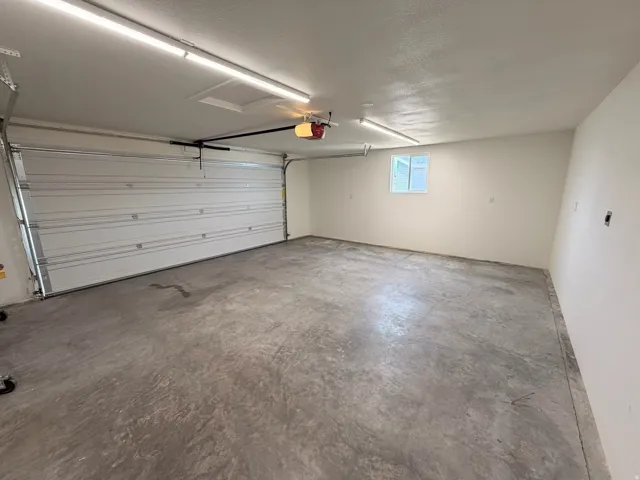 Spacious garage with a concrete floor, overhead lighting, and a window