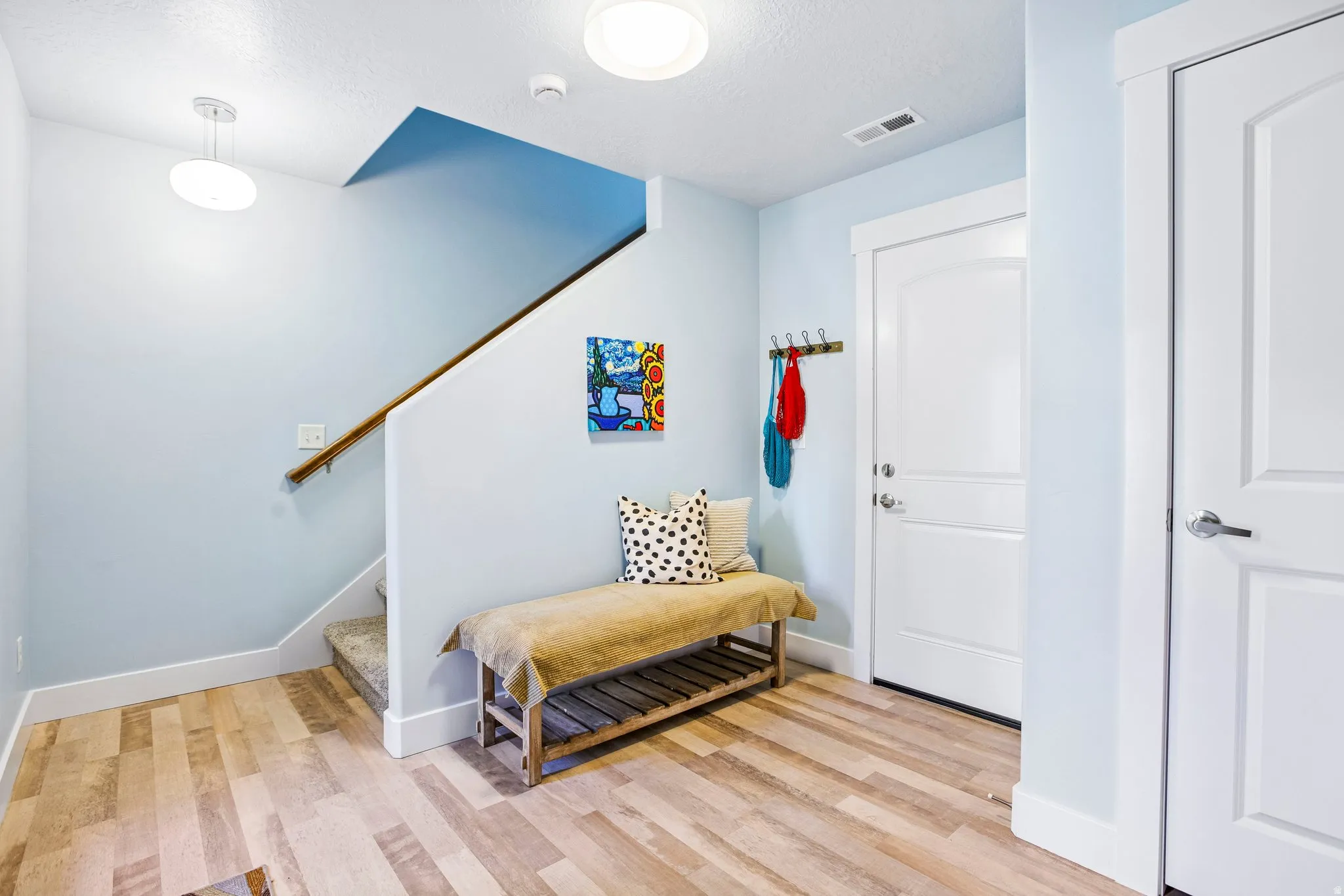 Wood-finish flooring throughout, a carpeted staircase with a wood handrail, and white paneled doors