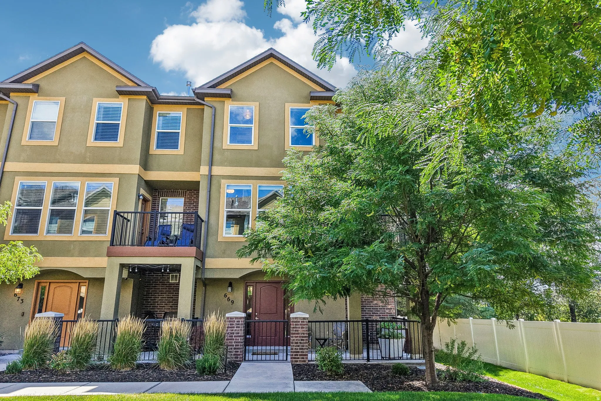 Charming three-story home featuring a warm stucco exterior with multiple gabled rooflines and contemporary architectural detailing