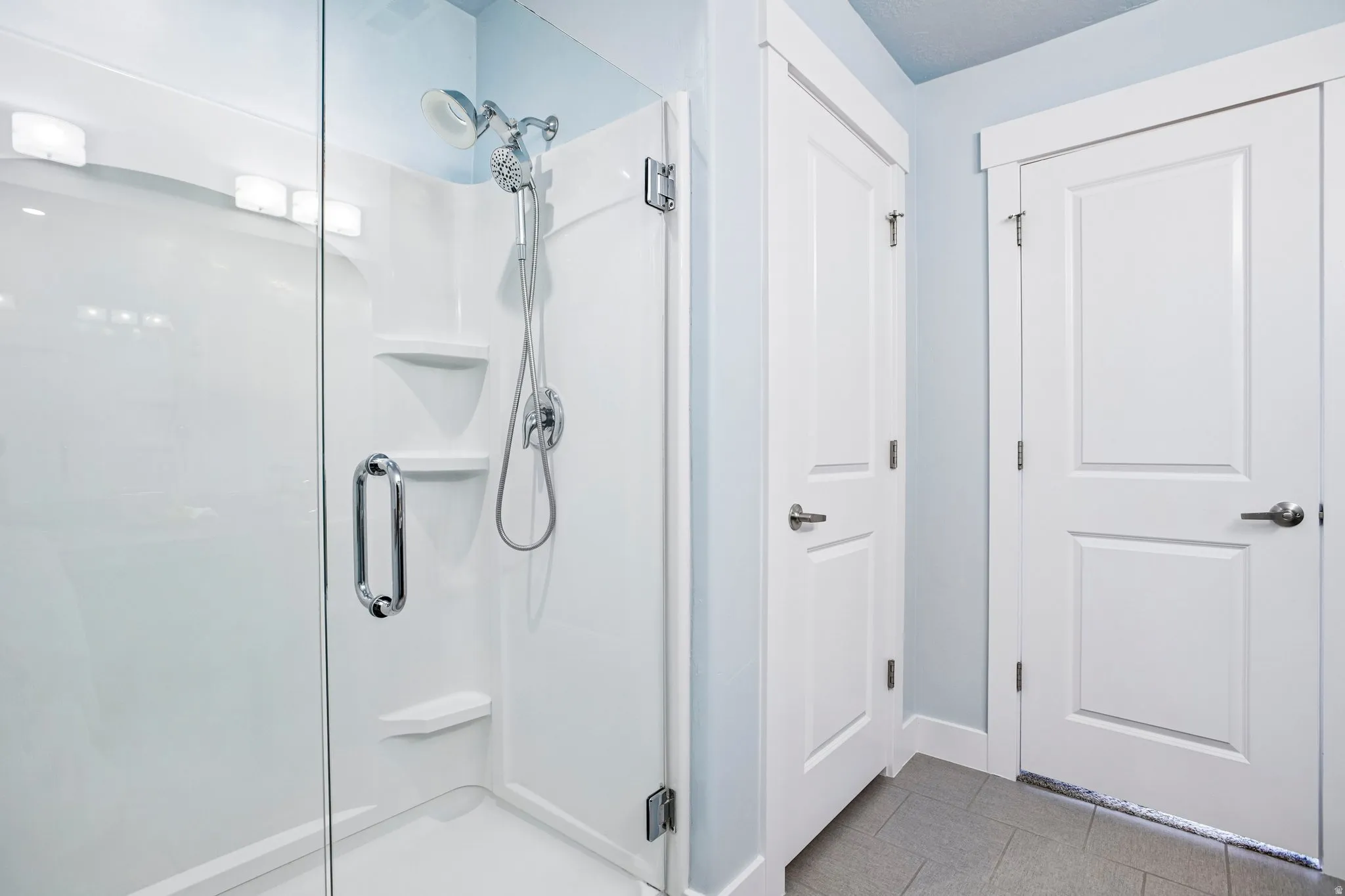Spa-inspired primary bathroom featuring a frameless glass-enclosed shower with dual showerheads, white subway tile surround, built-in niches, and polished chrome fixtures