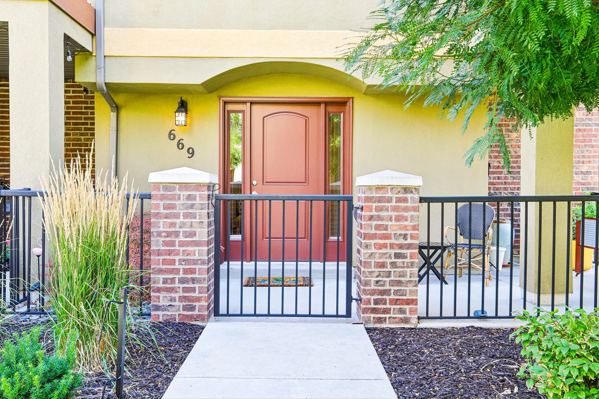 Entryway featuring a wood-panel door with sidelight, exterior wall sconce, and concrete walkway