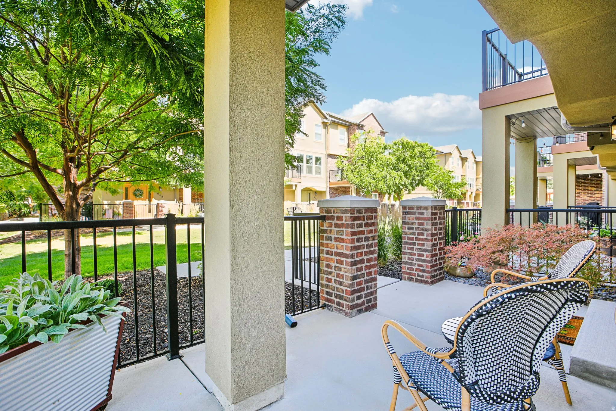 Patio with concrete flooring, black metal railings, and brick pillars