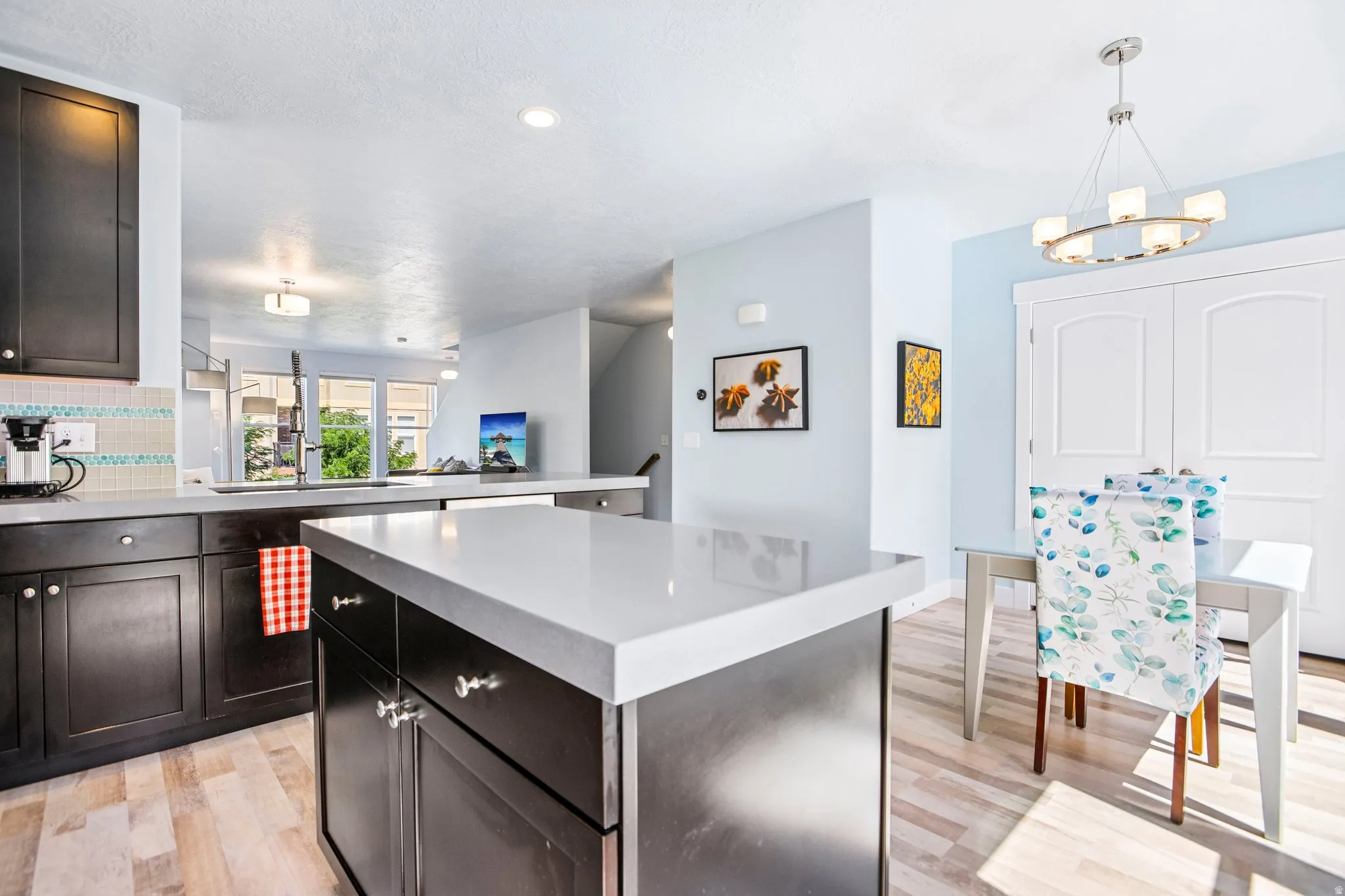 Kitchen featuring dark wood cabinetry, light countertops, wood-finish flooring, and a tiled backsplash
