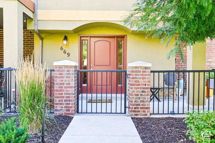 Entryway featuring a wood-panel door with sidelight, exterior wall sconce, and concrete walkway