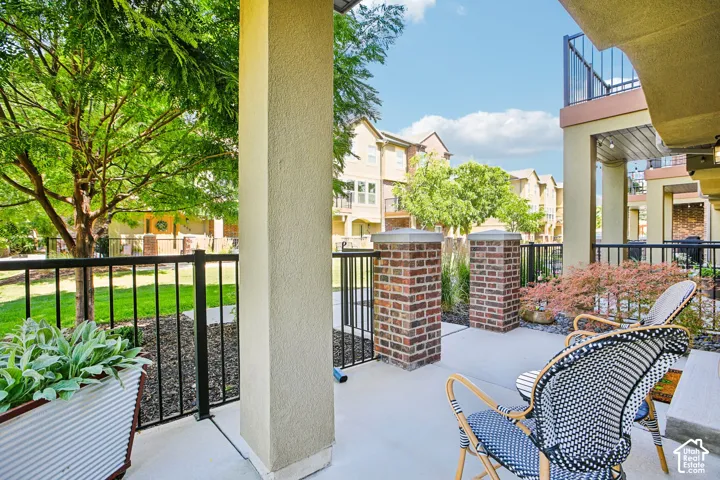 Patio with concrete flooring, black metal railings, and brick pillars