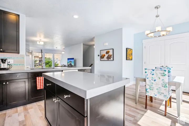 Kitchen featuring dark wood cabinetry, light countertops, wood-finish flooring, and a tiled backsplash