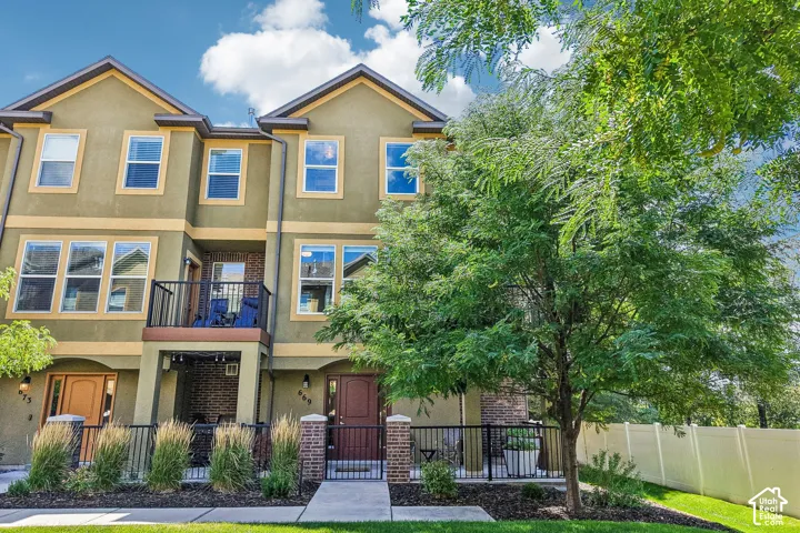 Charming three-story home featuring a warm stucco exterior with multiple gabled rooflines and contemporary architectural detailing