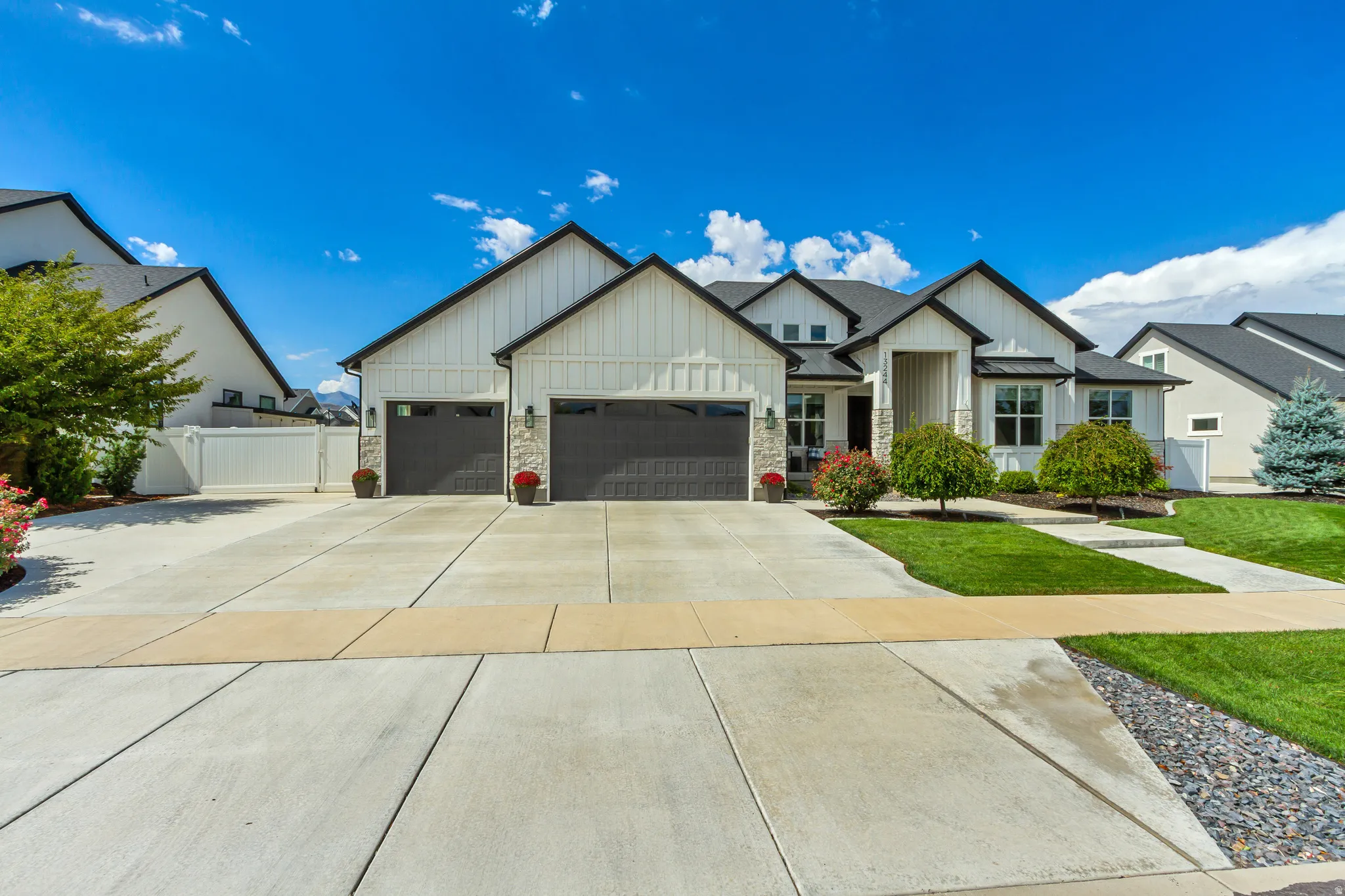 Modern farmhouse exterior with white vertical siding, black trim, and a two-car garage
