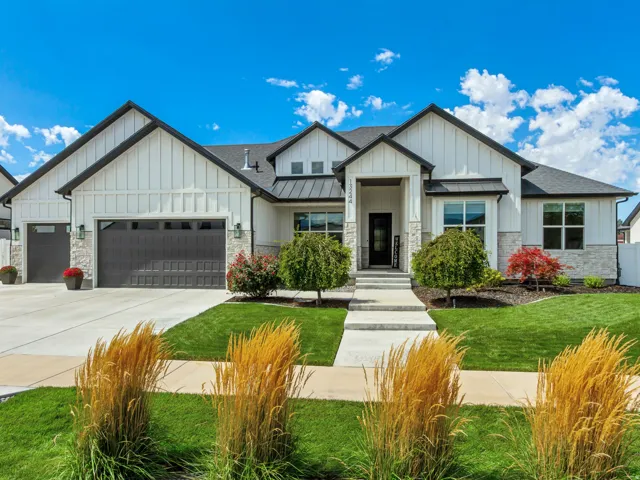 White board and batten exterior with stone accents, black roof, and dark-framed windows