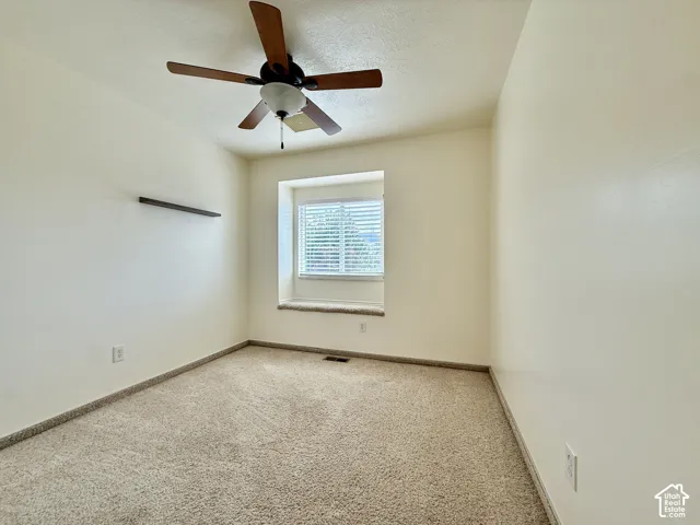 Recessed window with blinds, ceiling fan with integrated lighting, built-in wall shelf, and neutral carpeting