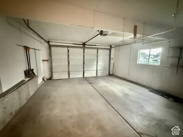 Two-car garage with concrete flooring, a paneled garage door, and a built-in window