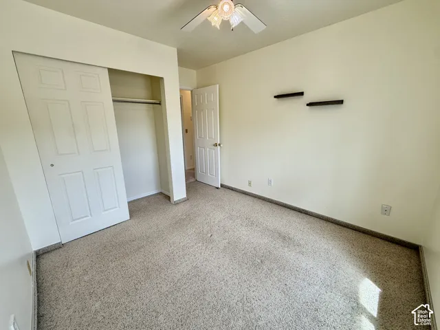 Plush carpet flooring, ceiling fan, and sliding closet doors