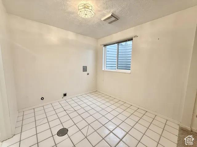 Room featuring white tile flooring, a window with blinds, and white walls