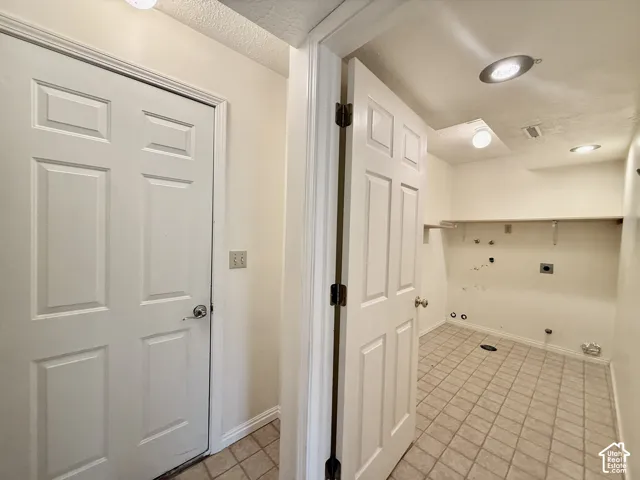 Utility space featuring tile flooring, a built-in shelf, and recessed lighting