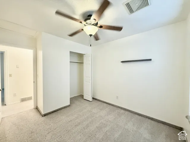 Recessed closet with bi-fold door, ceiling fan with integrated lighting, and neutral carpeting