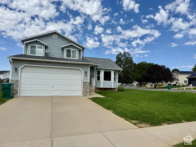 Two-story residence featuring light blue siding, stone-front detailing, a two-car garage, and a concrete driveway
