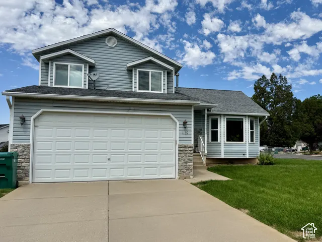Two-story residence featuring light blue siding, a multi-pane bay window, a two-car garage, and a concrete driveway