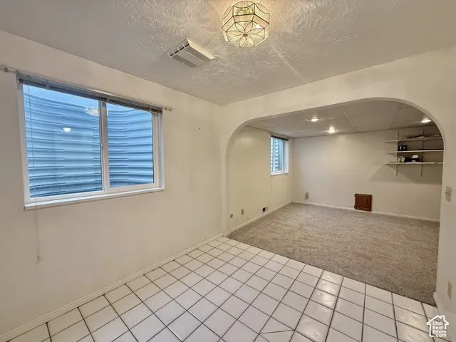White tile flooring, arched doorway, recessed lighting, wall-mounted shelving, and window with blinds