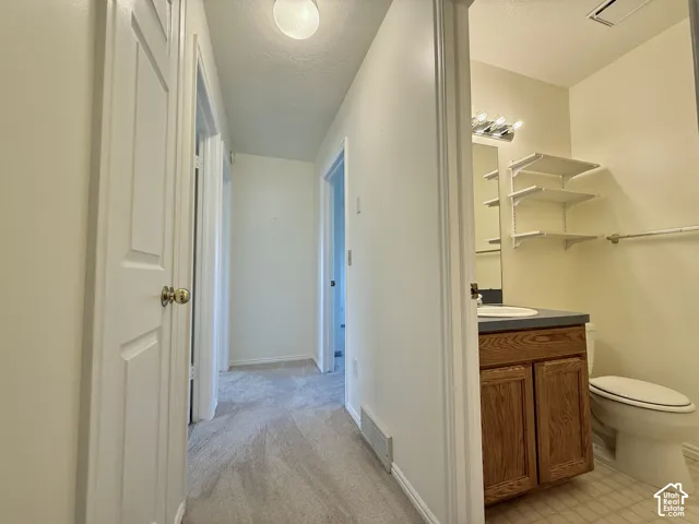 Bathroom featuring a vanity with wood-finish cabinetry, a single sink, and an overhead light fixture