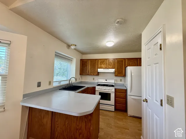 Kitchen featuring wood-finish cabinetry, light-toned countertops, and a double basin sink