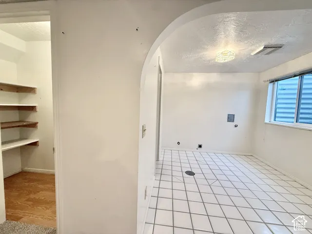 White square tile flooring, built-in shelving, arched doorway, and overhead lighting