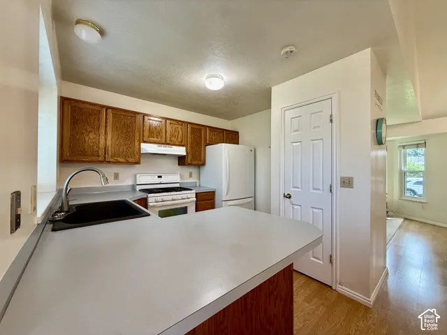 Kitchen featuring wood cabinetry, a white gas range, and a white refrigerator