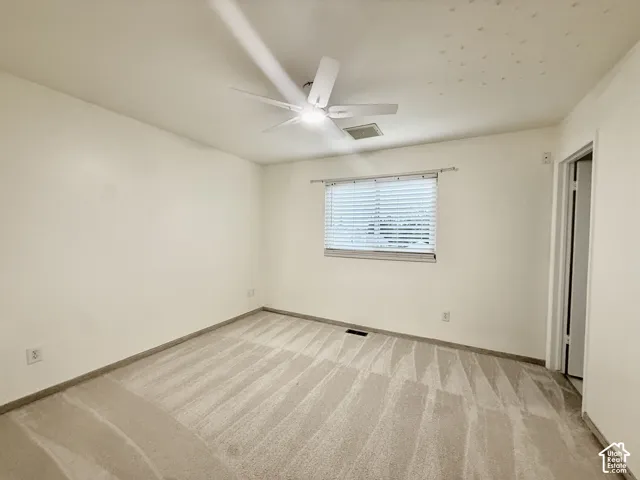 Ceiling fan with integrated lighting, window with blinds, and neutral wall color